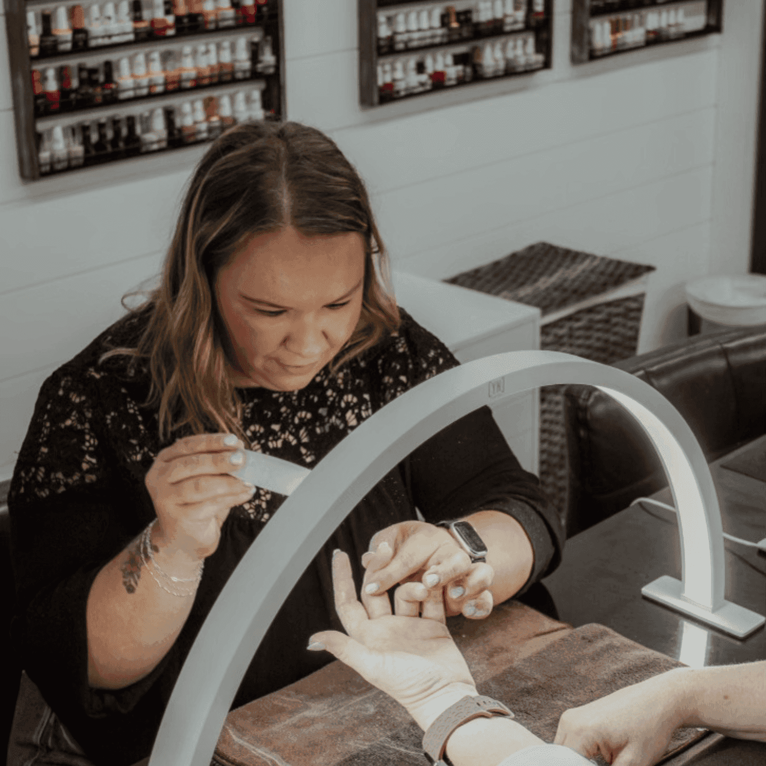 Manicure session with nail technician shaping client's nails in a salon.