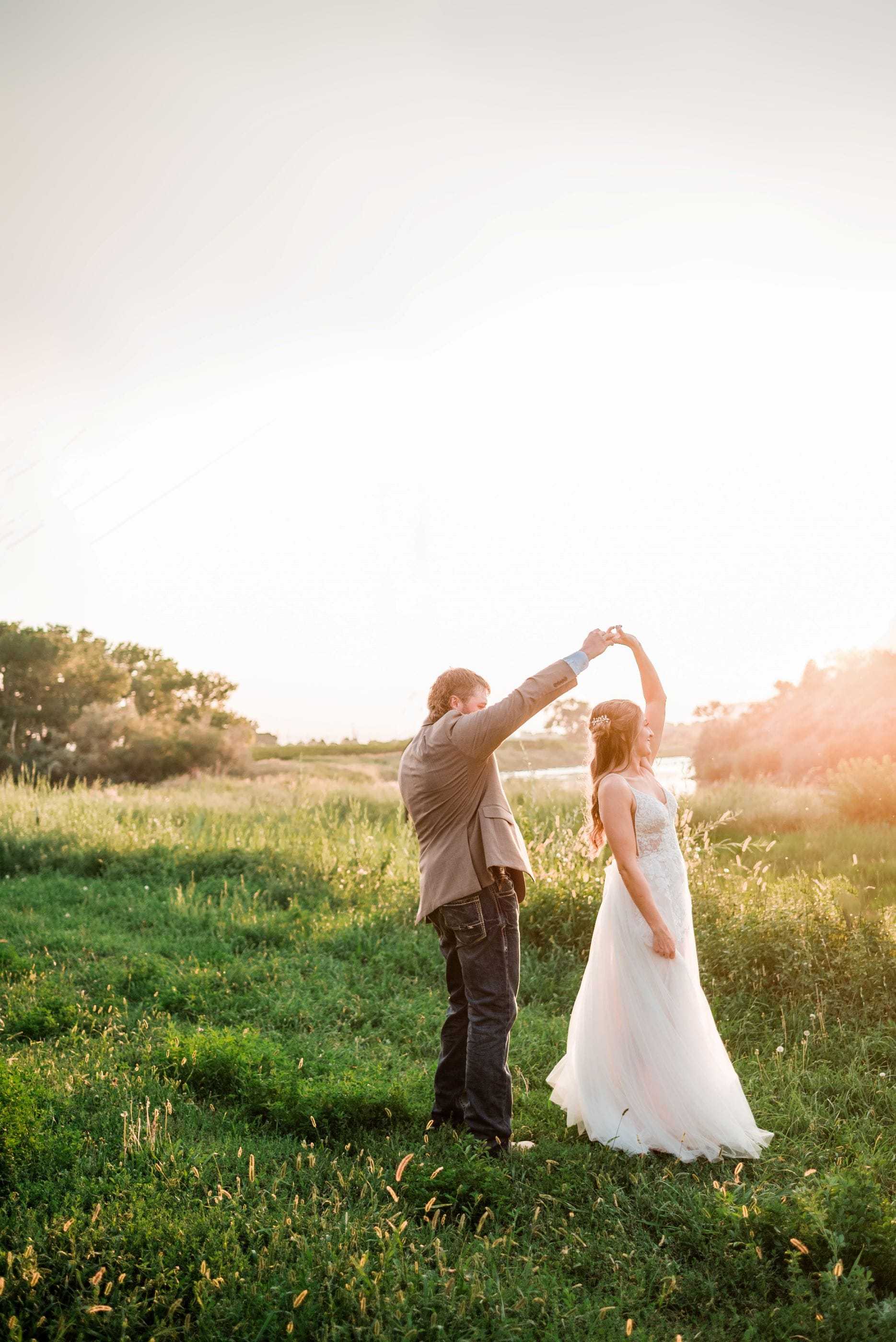 A couple dances in a sunlit grassy field, creating a romantic and serene scene.