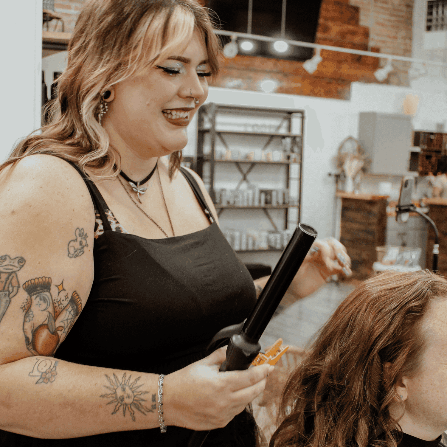 Hair stylist curling a client's hair in a salon.